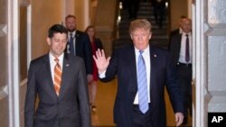 El presidente de EE.UU. Donald Trump (der.) y el presidente de la Cámara de Representantes, Paul Ryan caminan hacia una reunión de legisladores de su partido republicano en el Capitolio. Junio 19 de 2018.