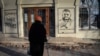 Seorang warga tampak mengamati grafiti yang menampilkan wajah Panglima Militer Ukraina Valery Zaluzhny di salah satu sudut di Kota Bakhmut, pada 20 Desember 2023. (Foto: AP/Andriy Andriyenko)