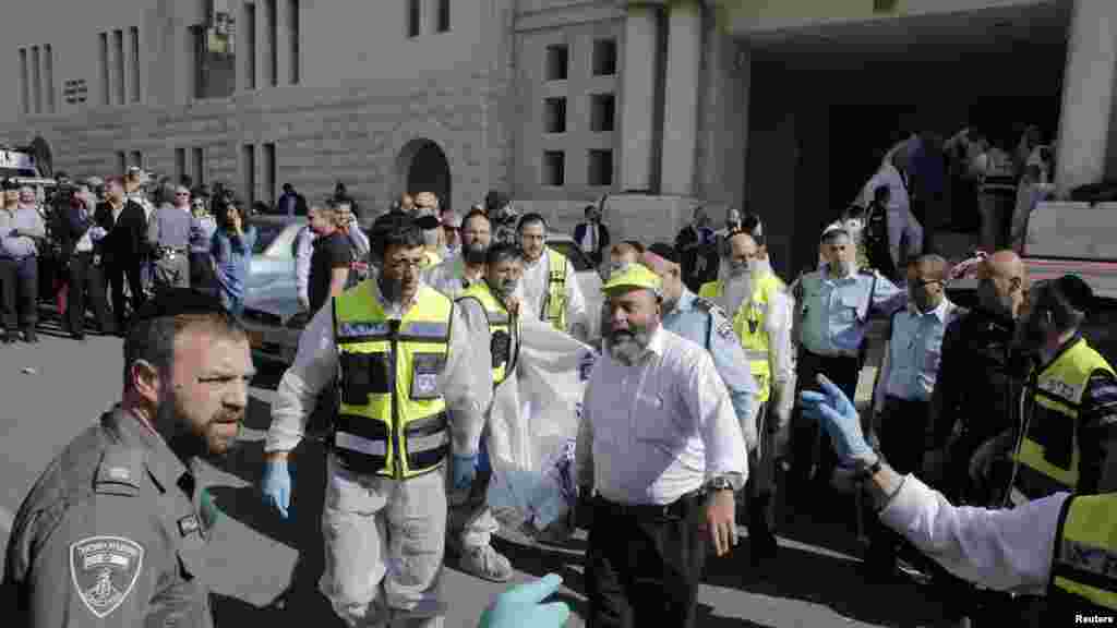 Israeli emergency personnel carry a covered body from the scene of an attack at a Jerusalem synagogue, Nov. 18, 2014.