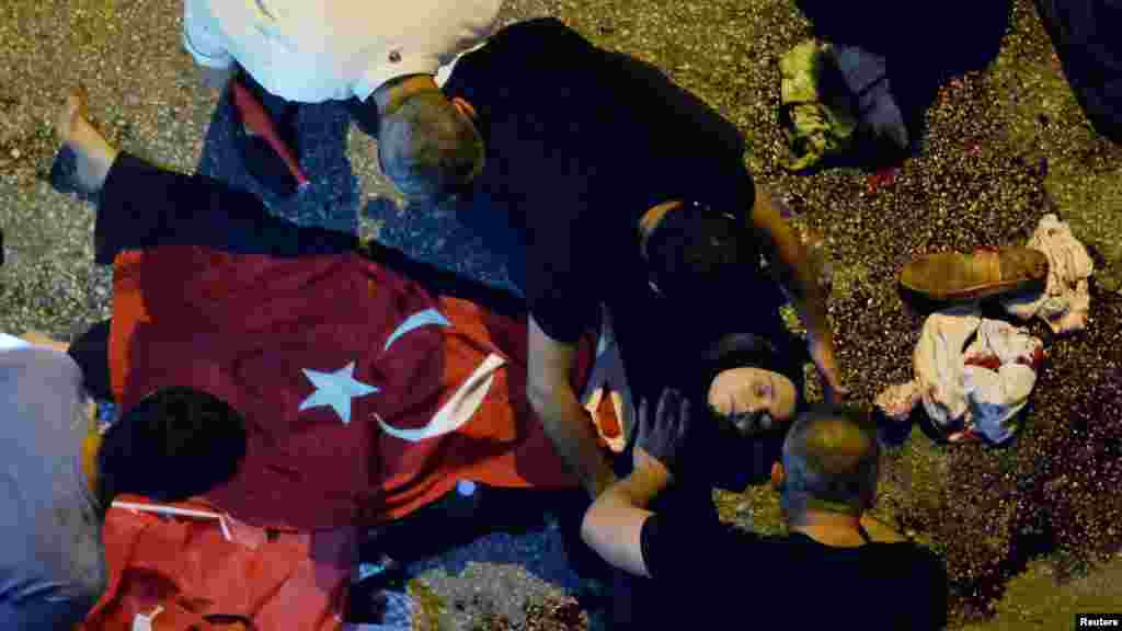 Des manifestants administrent des premiers soins à une femme blessée couverte d’un drapeau turc près de l‘état-major de l’armée à Ankara, Turquie, 16 juillet 2016. 