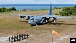 Philippine troops march as a Philippine Air Force C-130 transport plane carrying Defense Secretary Delfin Lorenzana, Armed Forces Chief Gen. Eduardo Ano and other officials, sits on the tarmac at the Philippine-claimed Thitu Island off the disputed Spratlys chain of islands in the South China Sea, April 21, 2017, in western Philippines.