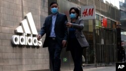 北京市民走过一家商场的阿迪达斯和H&M商店。 （2021年3月25日）