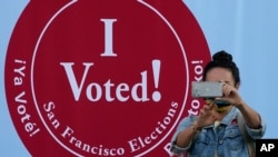 Žena fotografiše ispred znaka "Glasao sam" u Sekretarijatu za izbore u San Franciscu, 2. novembra 2020.