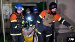 Рятувальники виносять постраждалого внаслідок атаки РФ у Харкові, 4 квітня 2024. Photo by SERGEY BOBOK / AFP