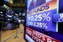 FILE - A TV on the floor of the New York Stock Exchange headlines a rate decision of the Federal Reserve, in New York, July 31, 2019.