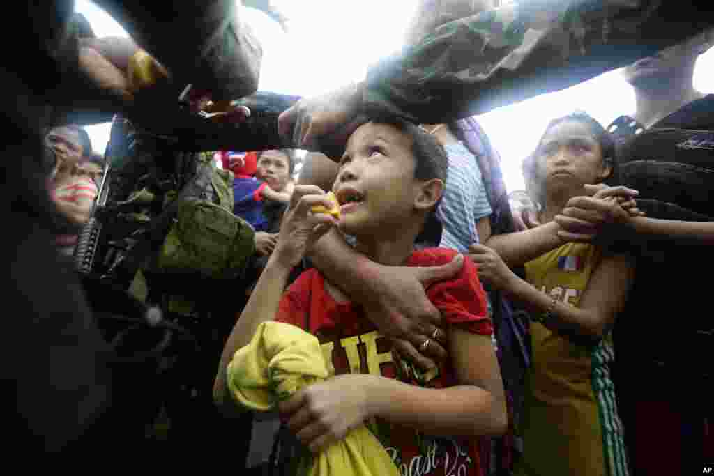 A Philippine air force officer hands out orange slices to typhoon survivors as they line up to board a C-130 military transport plane in Tacloban city, Nov. 12, 2013.