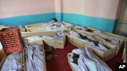 FILE - Bodies of civilians and security forces are placed at a hospital in Ghazni province, west of Kabul, Afghanistan, Aug. 12, 2018.