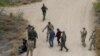 ARCHIVO: Agentes fronterizos y miembros de la Guardia Nacional de Texas detienen a inmigrantes que cruzaron la frontera desde México a EEUU en La Joya, Texas, el 17 de marzo de 2023.