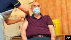 Brian Pinker, de 82 años, recibe la vacuna COVID-19 de la Universidad de Oxford / AstraZeneca de manos de la enfermera Sam Foster en el Hospital Churchill en Oxford, Inglaterra, el lunes 4 de enero de 2021.