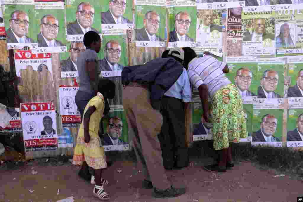 Residents of Epworth peep through a hole while watching a street performance a day before elections, Harare, July,30, 2013.