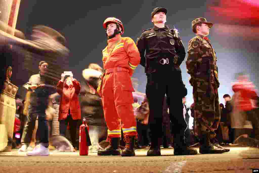 2018年2月28日,中国消防员(左)、警察(中)和武警在南京元宵节前的灯会上站岗。