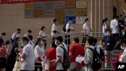 ARCHIVO - Estudiantes se forman para entrar a una escuela en el primer día de los exámenes de ingreso a la educación superior de China, conocido como el goakao, en Beijing, el martes 7 de junio de 2022.