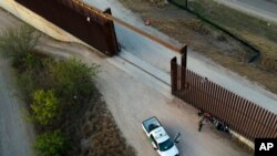Un oficial de Aduanas y Protección Fronteriza de Estados Unidos habla con los migrantes después de que fueron detenidos y puestos bajo custodia, el domingo 21 de marzo de 2021, en Abram-Perezville, Texas.