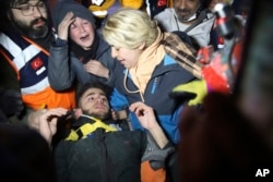Rescatistas y la madre de Adnan Mohammet Korkut rodean al joven tras ser rescatado en Gaziantep, en el sur de Turquía, el 10 de febrero de 2023.