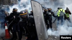 Protesters wearing yellow vests, a symbol of a French drivers' protest against higher fuel prices, clash with riot police on the Champs-Elysee in Paris, Nov. 24, 2018.