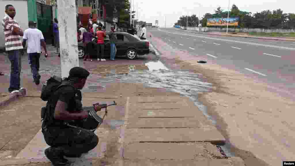 Un agent des forces de l'ordre prend position, arme à la main et prête à être utilisée, lors d'une émeute à Kinshasa prêt de la télévision nationale congolaise, le 30 décembre 2013. REUTERS/Jean Robert N'Kengo.