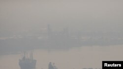 FILE - A cargo ship is seen through pollution along the Chao Phraya river in Bangkok, Thailand, Jan. 11, 2019.