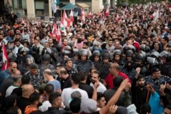 Riot police stand guard between two groups of demonstrators during ongoing anti-government protests in downtown Beirut, Lebanon, Oct. 24, 2019.