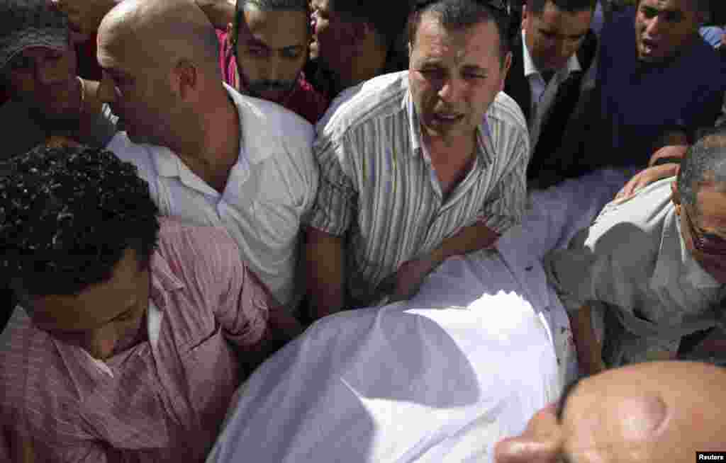 The body of Tunisian opposition politician, Mohamed Brahmi, is carried into an ambulance after he was shot dead outside of his home in Tunis, July 25, 2013. 