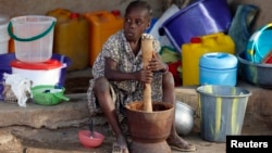 FILE - A girl displaced as a result of Boko Haram attacks in the northeast region of Nigeria, uses a mortar and pestle at a camp for internally displaced people in Yola, Adamawa State, Jan. 14, 2015.