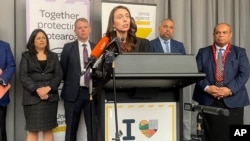 Flanked by lawmakers, New Zealand Prime Minister Jacinda Ardern delivers a speech on Aug. 12, 2021, in Wellington, New Zealand.