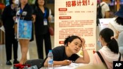 ARCHIVO - Una reclutadora habla con un solicitante durante una feria de empleo en un centro comercial en Beijing, el viernes 9 de junio de 2023.