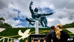 Ljudi stoje ispred Statue mira nako ceremonije kojom je obeleženo 76 godina od bacanja atomske bombe na Nagsaki, u Parku mira u Nagasakiju, 9. avgusta 2021.