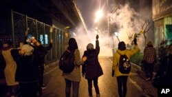 Manifestantes frente a la Universidad Amir Kabir en Teherán levantan flores mientras la policía dispara gas lacrimógeno el sábao 11 de enero. Foto: AP.