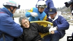 80-year-old Sumi Abe (C) is helped by emergency workers after being rescued from under the rubble in Ishinomaki City, Miyagi Prefecture, northern Japan, in this picture taken by Nikkei Shimbun on March 20 , 2011