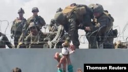 ARCHIVO: Un bebé es entregado al ejército estadounidense sobre el muro perimetral del aeropuerto de Kabul.
