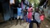 FILE - Laboratory technician Mohamed SK Sesay, who survived Ebola but saw many of his colleagues die and now has joint and muscle pains and loss of sight, holds the child of one of his work colleagues who died of the disease, in Kenema, Sierra Leone, Aug. 9, 2015.