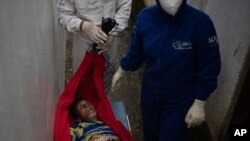 Seorang petugas darurat membawa Jose Rocha di tempat tidur gantung ke rumah sakit khusus bagi pasien yang diduga terpapar virus COVID-19 di Manacapuru, negara bagian Amazonas, Brasil, Senin, 1 Juni 2020. (Foto AP / Felipe Dana)