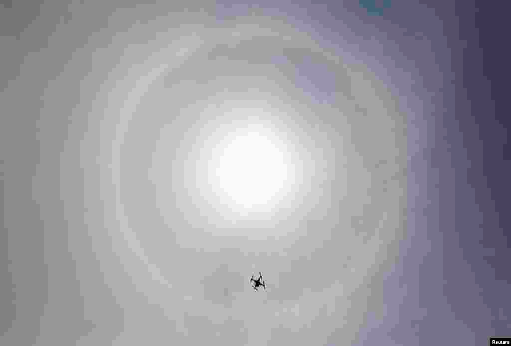 A drone flies in the sky as a solar halo is observed in Lima, March 5, 2014. The optical phenomenon is caused by refraction of sunlight through ice crystals in high clouds.