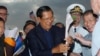 File: Cambodia's Prime Minister Hun Sen, center, gives a flower to a passenger who disembarked from the MS Westerdam, owned by Holland America Line, at the port of Sihanoukville, Cambodia, Feb. 14, 2020.