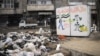 Trash is piled high in the streets of Aleppo where collection stopped long ago. The sign reads, "The money of the revolution is for the people," November 10, 2012. (AP)