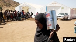 Mwanamke akiwa amebeba kopo la chakula cha msaada ulichotolewa kwa ajili ya wakimbizi wa Ethiopia, tarehe 3 Desemba 2020. Picha na Reuters.