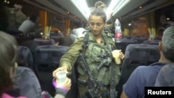 Seorang tentara Israel membagikan air di dalam bus, saat mengevakuasi para relawan dari kelompok pertahanan sipil Suriah "White Helmets", dari Dataran Tinggi Golan, Israel, 22 Juli 2018. (Israeli Army Handout via REUTERS)