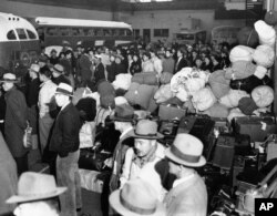 FILE - People of Japanese ancestry board buses in Los Angeles, for Owens Valley, 235 miles north, where the government's first alien reception center is under construction, March 21, 1942.