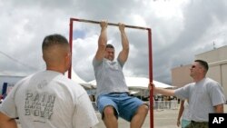FILE - Matt Elam, center, competes in a US Marine pull-up contest while Marine recruiters Sgt. Marco Hartanto, left, and Gysgt. Brian Lancioni watch during BayFest 2006 held at Marine Corps Base Hawaii, Tuesday, July 4, 2006, in Kaneohe, Hawaii.