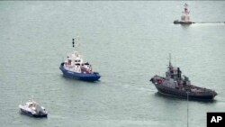 Sebuah kapal Ukraina yang disita (kanan), ditarik oleh kapal penjaga pantai Rusia keluar dari pelabuhan di Kerch, Crimea, Minggu, 17 November 2019. (Krym 24 tv station via AP Television)