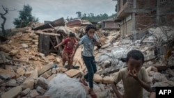 Anak-anak Nepal menutup hidung akibat bau jenazah korban gempa saat melewati puing-puing di Chautara, 80 kilometer dari ibukota Kathmandu (foto: dok). Nepal kembali diguncang gempa Selasa (12/5) sore. 