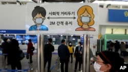A social distancing sign is seen as people wait at the Seoul Railway Station, Nov. 13, 2020, as South Korea reported its biggest daily jump in COVID-19 cases in 70 days, and the government began fining people who fail to wear masks in public.