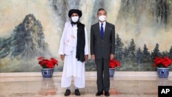 In this photo released by China's Xinhua News Agency, Taliban co-founder Mullah Abdul Ghani Baradar, left, and Chinese Foreign Minister Wang Yi pose for a photo during their meeting in Tianjin, China, Wednesday, July 28, 2021. (Li Ran/Xinhua via AP)