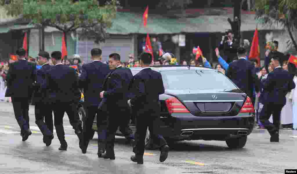 North Korean bodyguards run alongside a limousine transporting North Korea's leader Kim Jong Un upon his arrival at the town on the border with China, in Dong Dang, Vietnam.