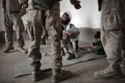 FILE - A local Afghan imam listens to an interpreter for the U.S. Marines in Marjah, Helmand province, southern Afghanistan, April 12, 2010.