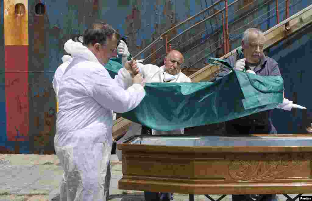 People carry the body of a dead migrant from a merchant ship as they arrive in the Sicilian harbor of Catania, southern Italy, May 5, 2015. 