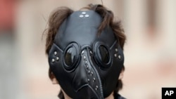 A man wears a mask as demonstrators gather to protest the COVID-19 preventative measures downtown Prague, Czech Republic. (AP Photo/Petr David Josek)