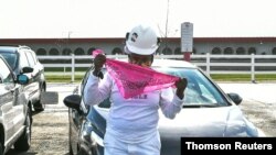 Una empleada de Tyson Foods se coloca una segunda mascarilla protectora afuera de la planta de procesamiento de carne en Waterloo, Iowa.