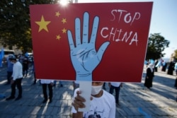 FILE - A protester from the Uighur community living in Turkey holds up an anti-China placard during a protest in Istanbul, Turkey, Oct. 1, 2020.
