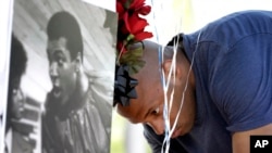 Un mémorial improvisé en la mémoire de Mohamed Ali, érigé à l'extérieur du centre médical de Scottsdale Osborn où Mike Ingraham, admirateur de l’ex-champion du monde boxe décédé, s’incline avec des ballons, à Scottsdale, en Arizona, 4 juin 2016. (AP Photo / Matt York)
